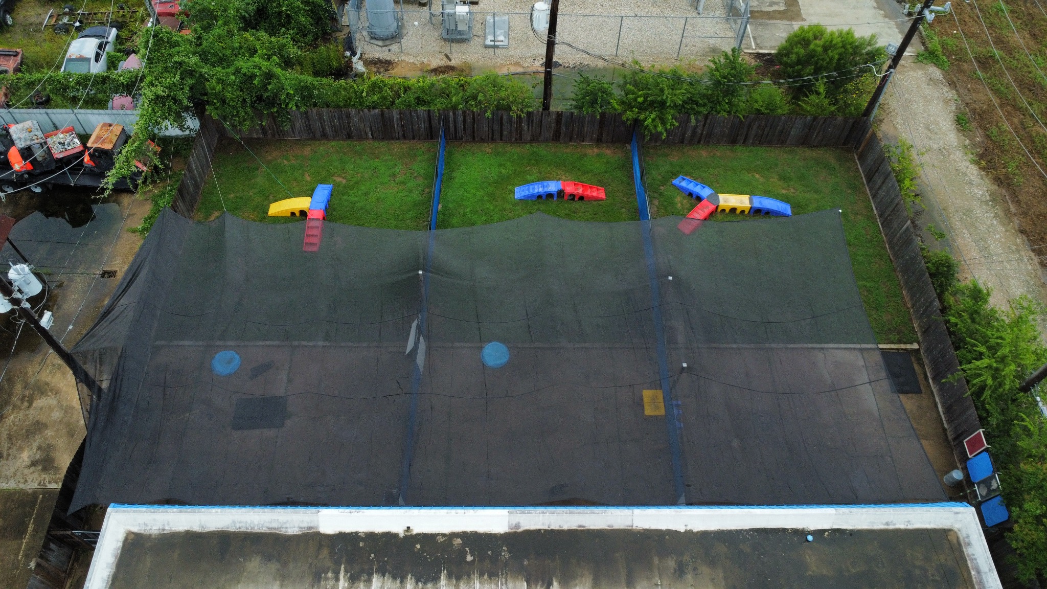Aerial view of three divided outdoor play yards with large shade canopies and grassy areas at Preppy Pet West Houston